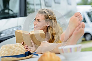 woman reading book in campervan campsite