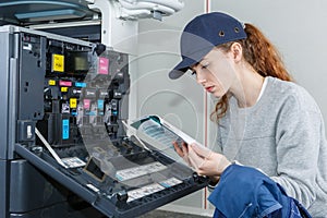 Woman reading instruction manual for photocopier photo