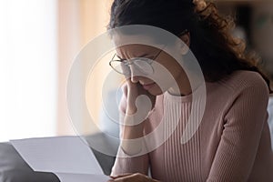 Woman reading letter feels upset by debt or financial problems