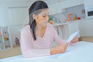 Woman reading letter at home in living room