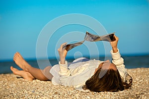 Una donna lettura rivista sul Spiaggia 