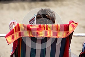 Woman reading magazine on beach in deckchair