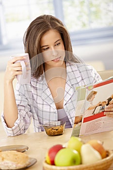 Woman reading magazine at breakfast