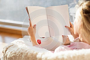 Woman reading magazine with empty white blank pages. Mockup for your own content.