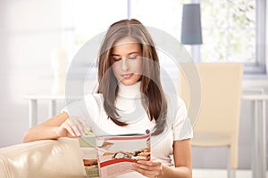Woman reading magazine at home photo