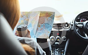 A woman reading a map for direction and drinking coffee in the car