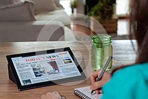 Woman reading the news on a tablet at home. Imaginary online, mobile website, application or news portal on modern touch screen.