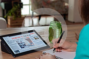 Woman reading the news on a tablet at home. Imaginary online, mobile website, application or news portal on modern touch screen.