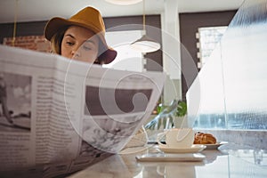 Woman reading newspaper in cafe