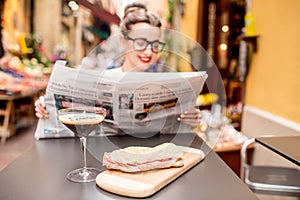 Woman reading newspaper at the cafe outdoors