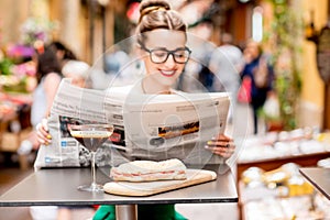 Woman reading newspaper at the cafe outdoors