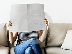 Woman reading newspaper on the couch