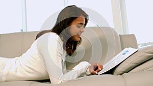 Woman reading newspaper on couch