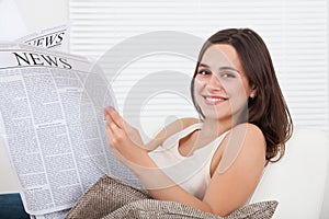 Woman reading newspaper at home