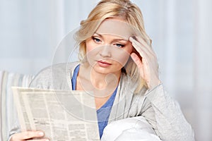 Woman reading newspaper at home