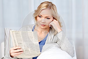 Woman reading newspaper at home