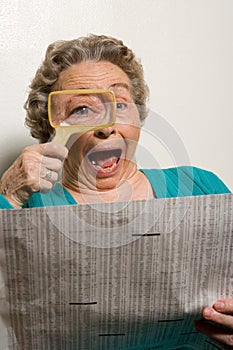 Woman reading newspaper with magnifying glass