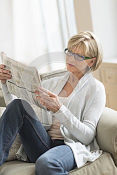Woman Reading Newspaper While Relaxing On Sofa
