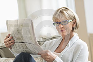 Woman Reading Newspaper While Relaxing On Sofa