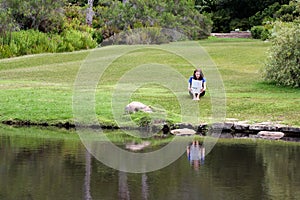 Woman reading newspaper sitting in grass