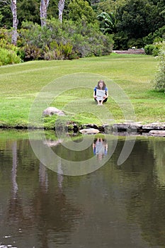 Woman reading newspaper sitting in grass