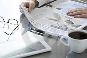 Woman reading newspaper on table