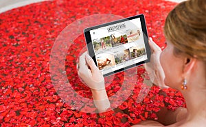 Woman reading online blog on tablet while taking bath. All contents are made up.