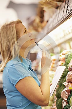 Woman Reading Shopping List In Supermarket