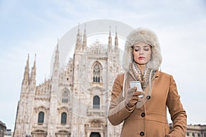 Woman reading sms on smartphone while standing near Duomo, Milan