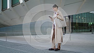 Woman reading sms street. Pretty girl holding modern smartphone surfing internet