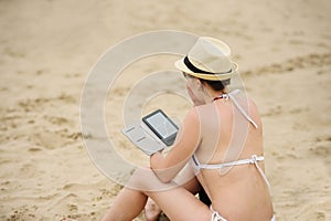woman reading tablet reader on the beach