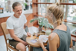 Woman is reading Tarot cards with a cusomer in cafe