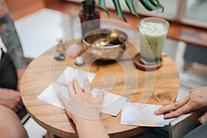 Woman is reading Tarot cards with a cusomer in cafe