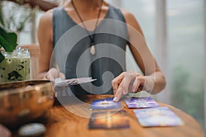 Woman is reading Tarot cards on a table in cafe