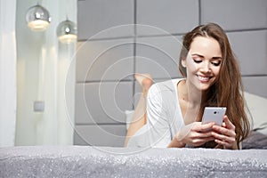 Woman reading a text message in her bright bedroom