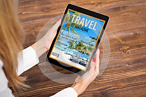Woman reading travel magazine on tablet photo