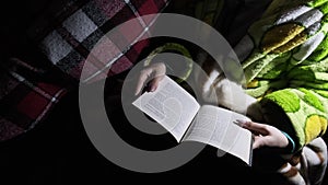 Woman Reads a Book Lying on a Sofa at Night in the Light of a Flashlight