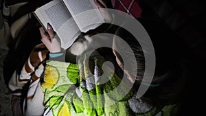 Woman Reads a Book Lying on a Sofa at Night in the Light of a Flashlight