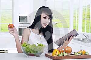 Woman reads book and prepare salad