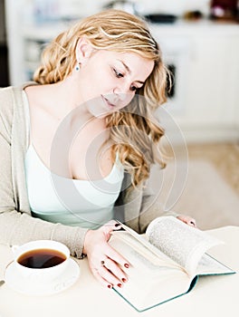 Woman reads an interesting book and drinks coffee