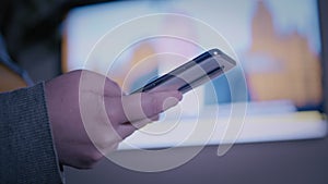 woman reads news on a phone on the background of a working TV, important information, breaking news on tv, a woman is