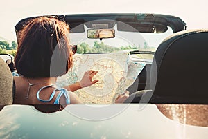 Woman reads roads map sitting in cabriolet car