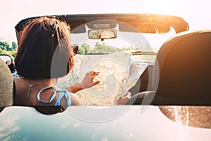 Woman reads roads map sitting in cabriolet car