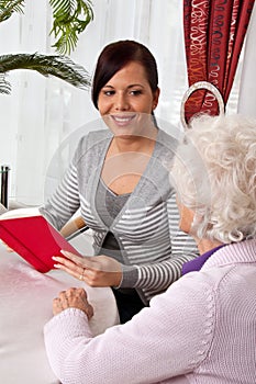 Woman reads to seniors from a book.