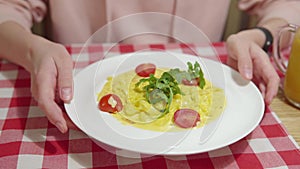 Woman is ready to eat pumpkin pasta with sauce, shrimp, cherry tomatoes and basil in the restaurant.