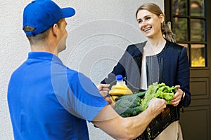 Woman receive online grocery order box from delivery man at home