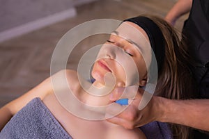 Woman receives facial cupping massage facial rejuvenation at acupuncture wellness spa.