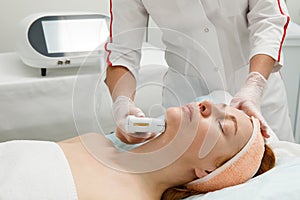 A woman receives laser treatment of the face in a cosmetology clinic, a concept of skin rejuvenation is being developed