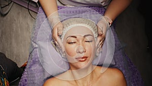 Woman receiving anti-ageing facial massage in spa salon relax. Wellness body skin care face beauty treatment. Black