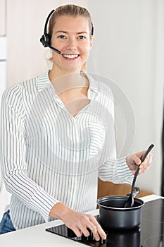 woman receiving call on handfree headset while cooking meal